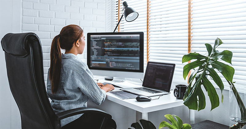 Young woman sits at desk optimizing a website on her laptop.