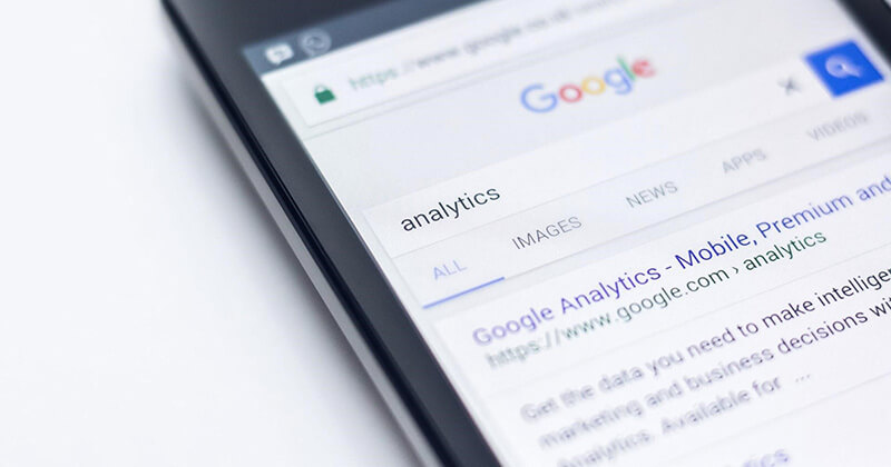 Mobile device displays Google search engine results page for the query "analytics."